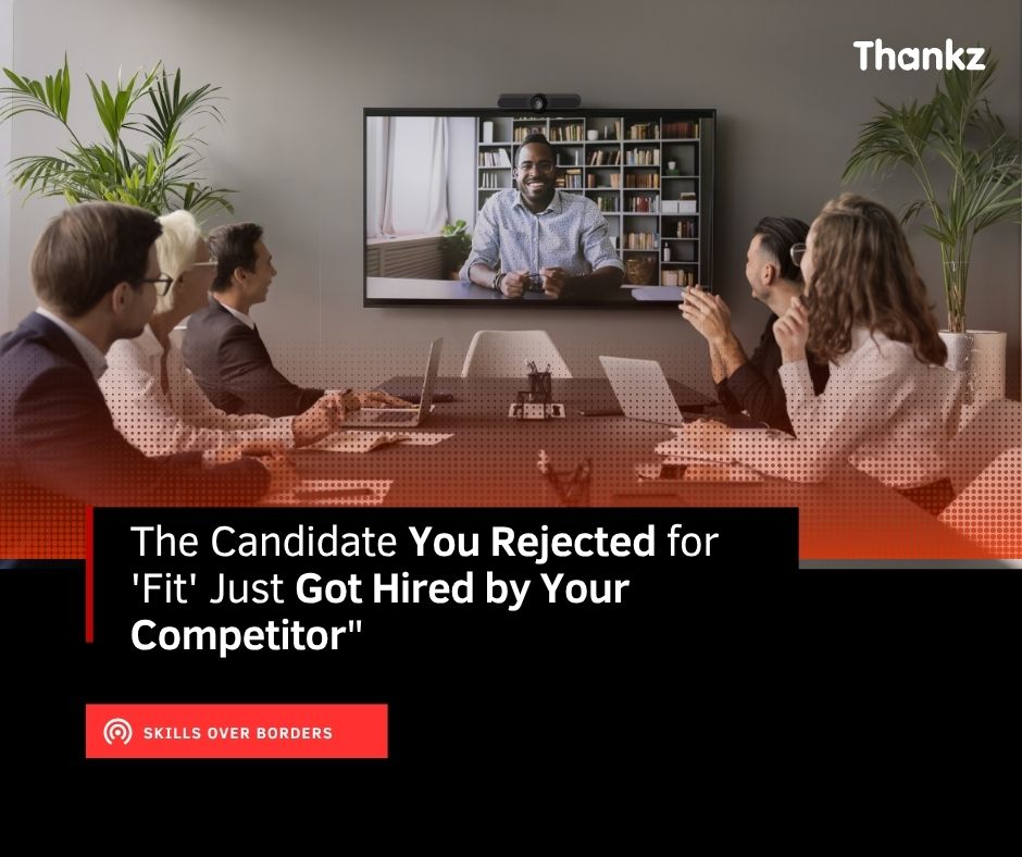 A hiring team in a conference room interviews a remote candidate on a wall-mounted video call, illustrating skills-based global hiring in 2026.